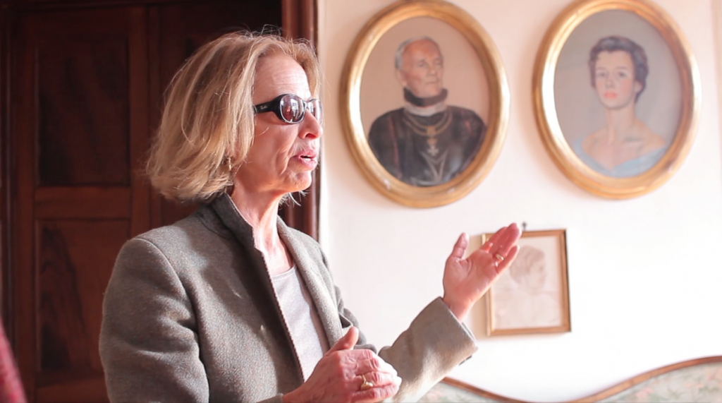 The Countess, Carolina Levetzow Lantieri, explaining the history of her family. In the background, the portraits of the Baron, Charles Levetzow Lantieri, and the Countess, Dorothea Saurma-Hoym.