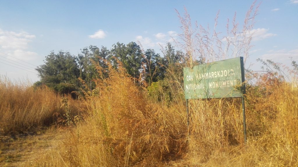 In the Picture is a billboard with words saying 'Dag Hammarskjold National Monument'