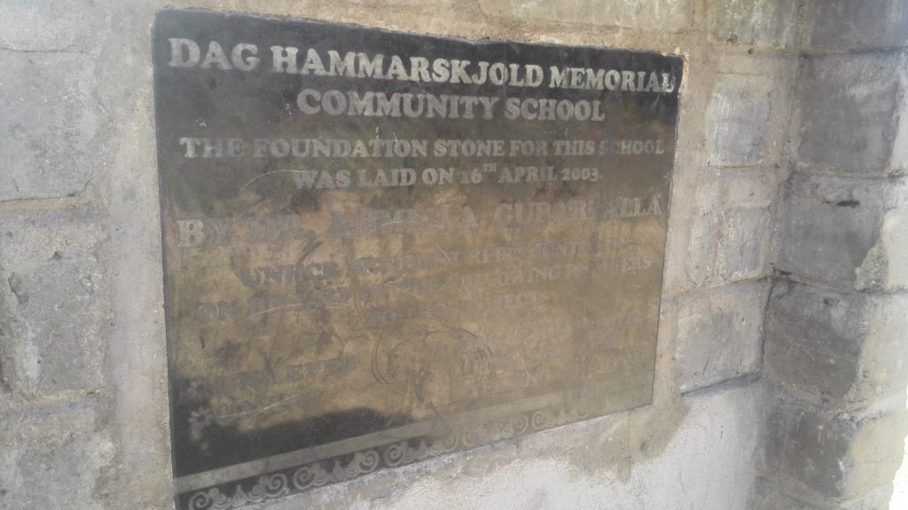 In the picture is a Community School billboard nearby the Dag Hammarskjold memorial site.