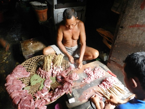 A worker cutting goat meat to prepare Bustaman Goat Gulai