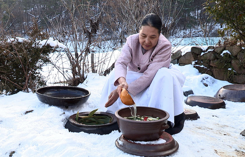 A grandmother opens a Kimchi pot. Photo credit: Cultural Heritage Administration, Republic of Korea