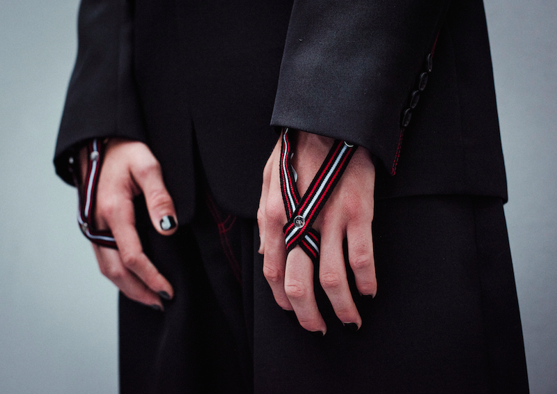 Black wool jackets with red topstitch details matched with red and white-striped ribbed cuffs for the hands, from Dior Homme's Summer 2017 collection. Photography by Morgan O’Donovan