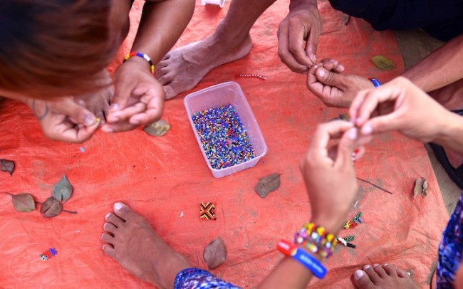 The creative hands of these Lumads who have set camp in Manila are stringing beads to make their colorful jewelry. Photo by Bernard Testa, InterAksyon.com.