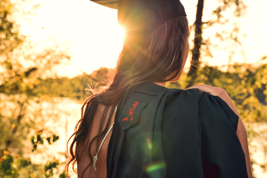 girl walking away with backpack. Sunlight shines on her
