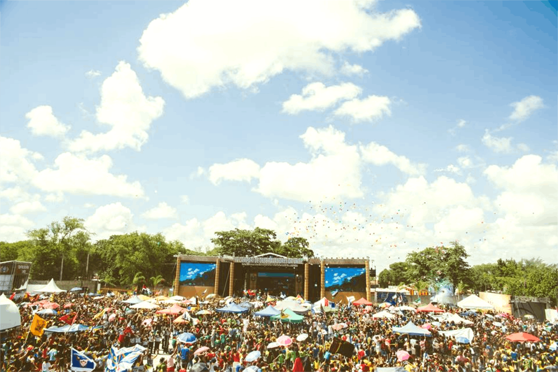 A concert stage on a huge field filled with thousands of people