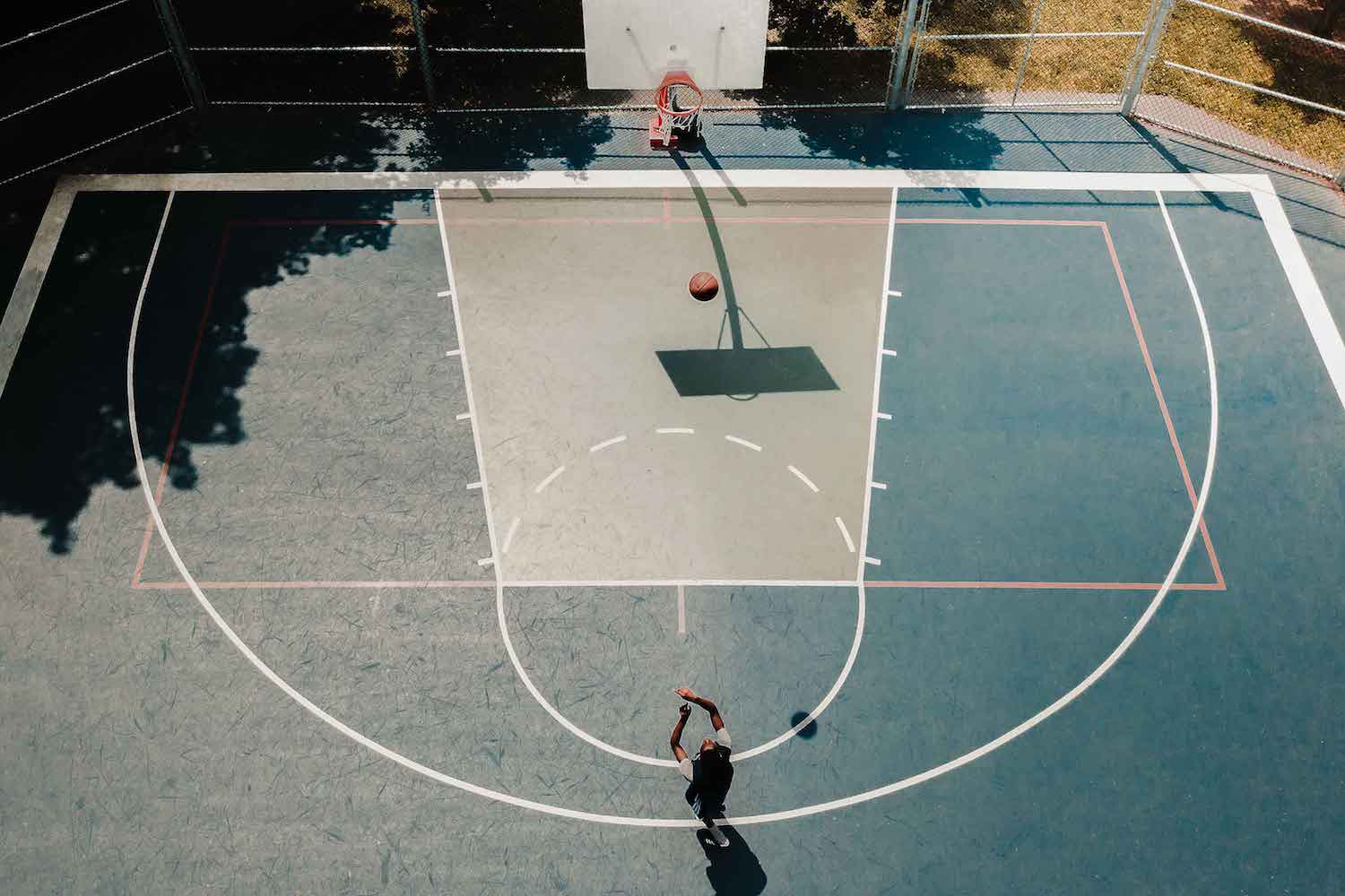 top view of man shooting a ball into a basketball ring