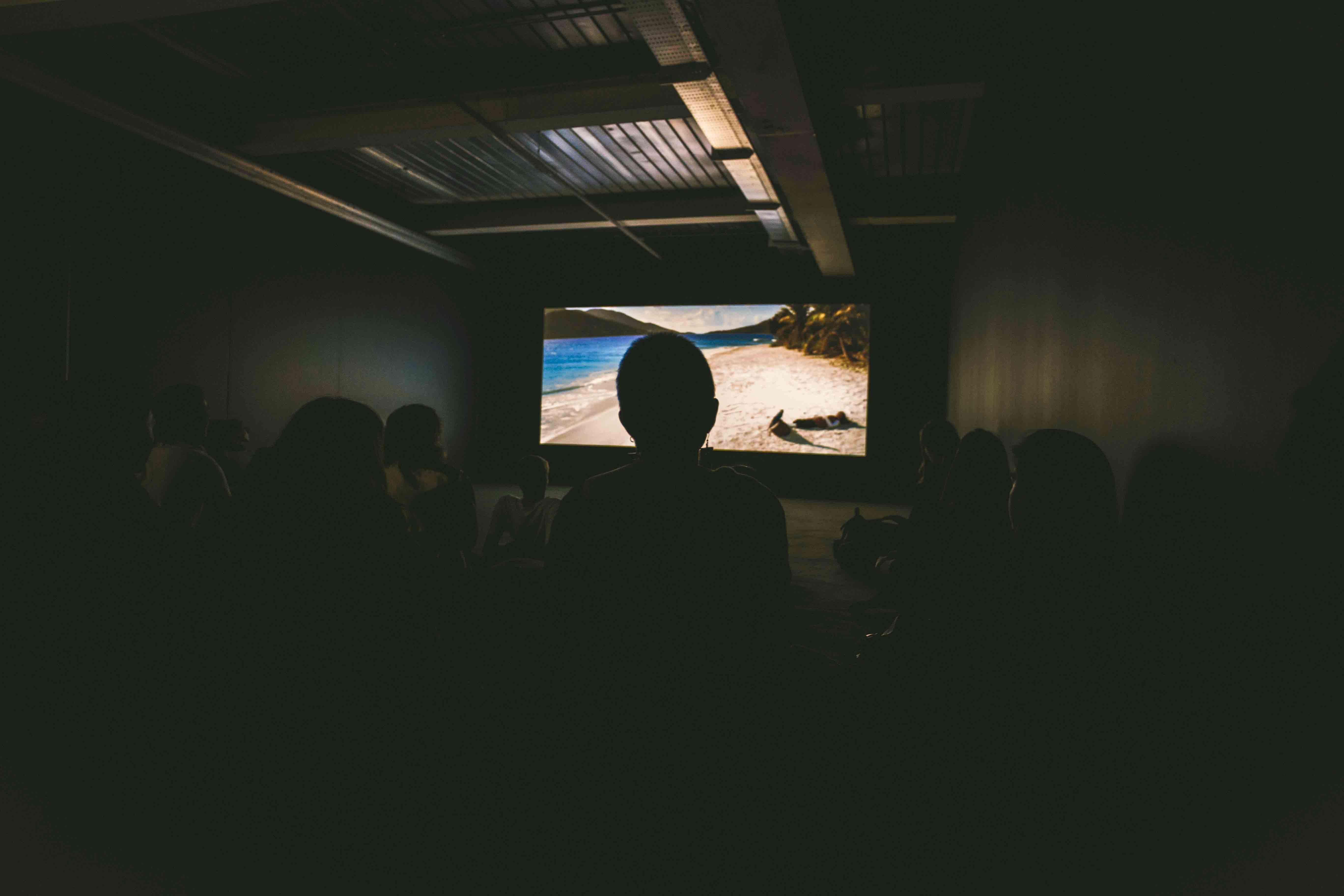 dark room with movie projected in front of a crowd
