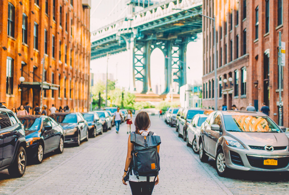 girl carrying a backpack while standing on the middle of a street