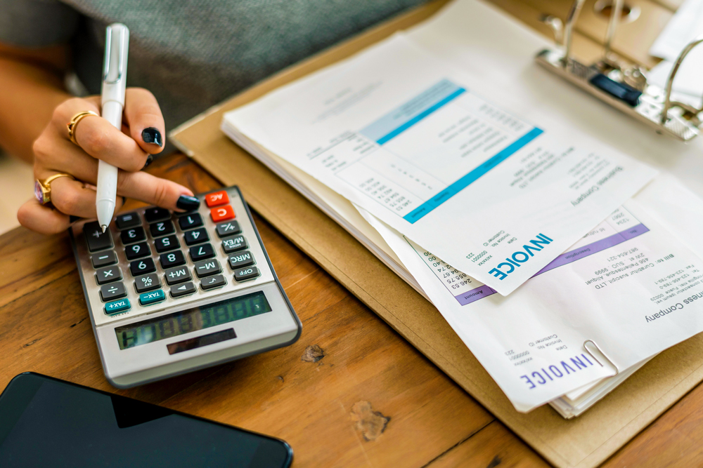 finger pressing a calculator, computing invoices