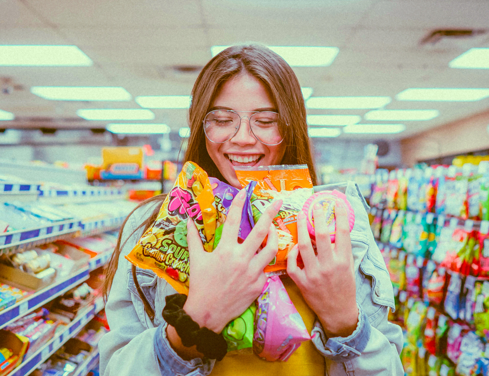 girl hugging a heap of candies in the middle of a store