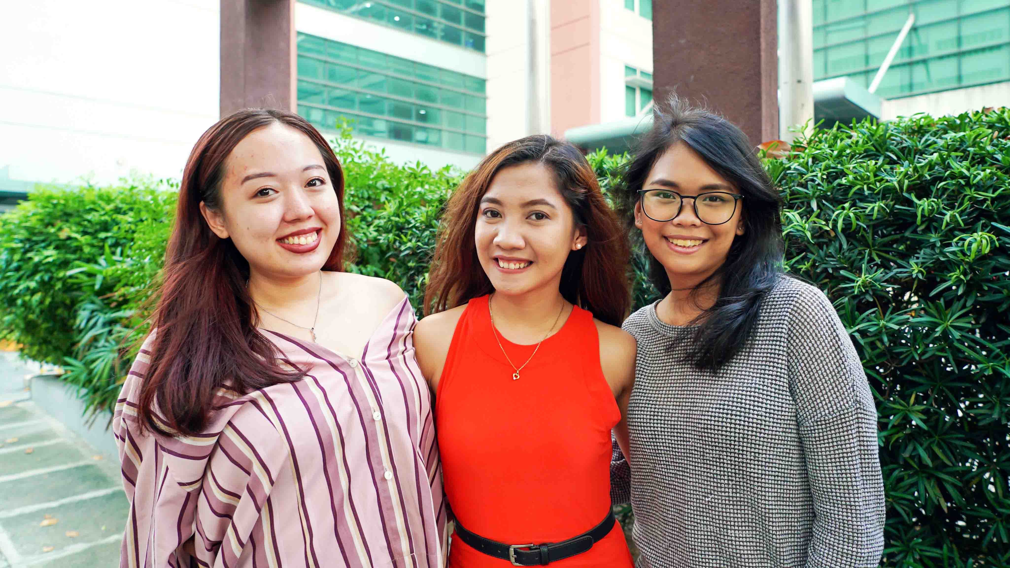 three young women standing alongside each other in an outdoor setting