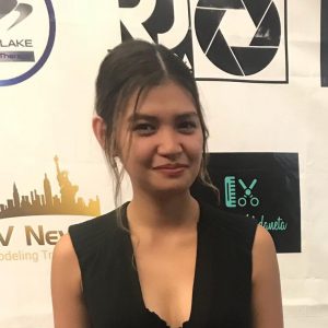 girl with dark brown hair in a ponytail smiling