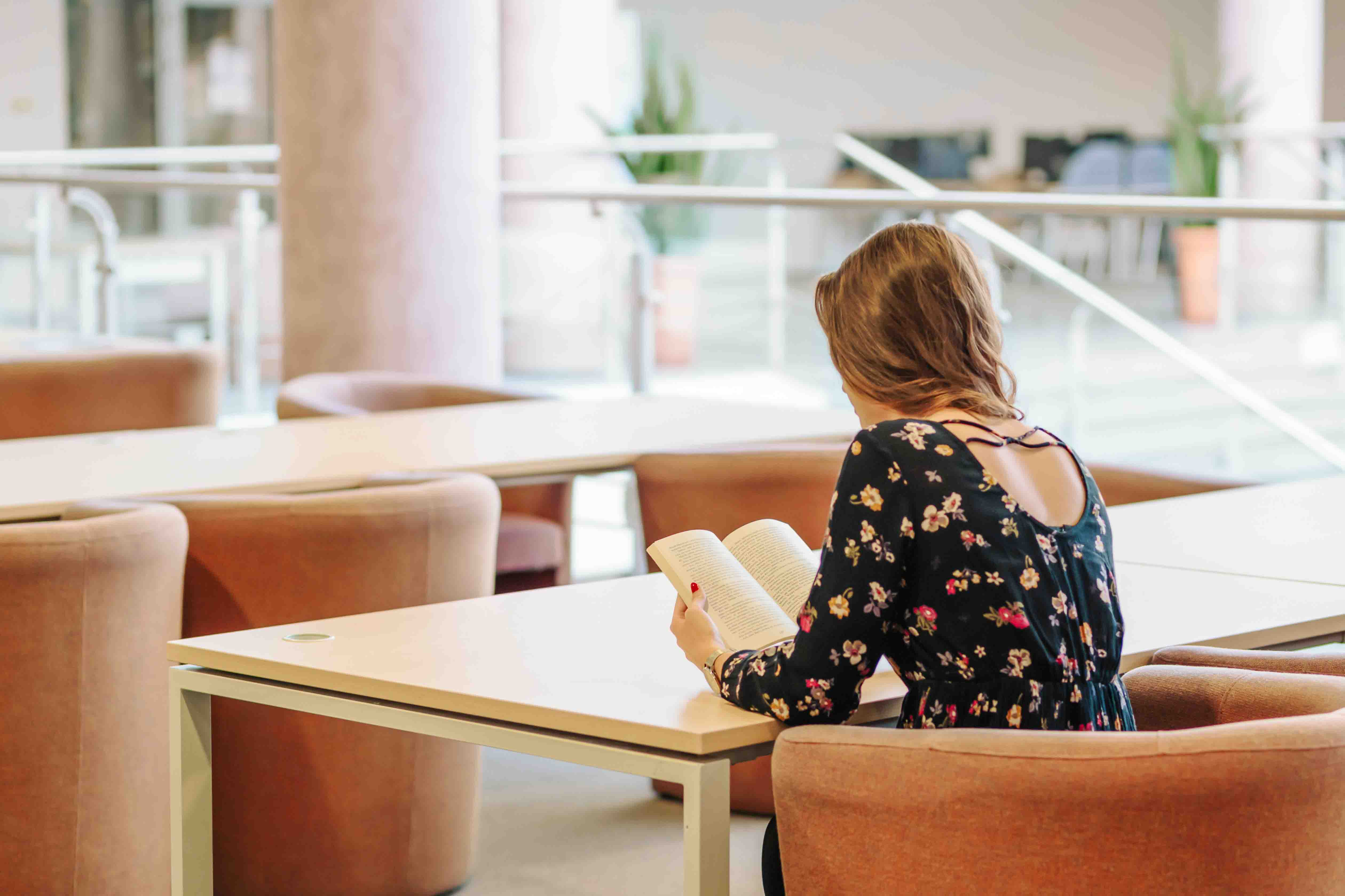 girl reading a book at a table