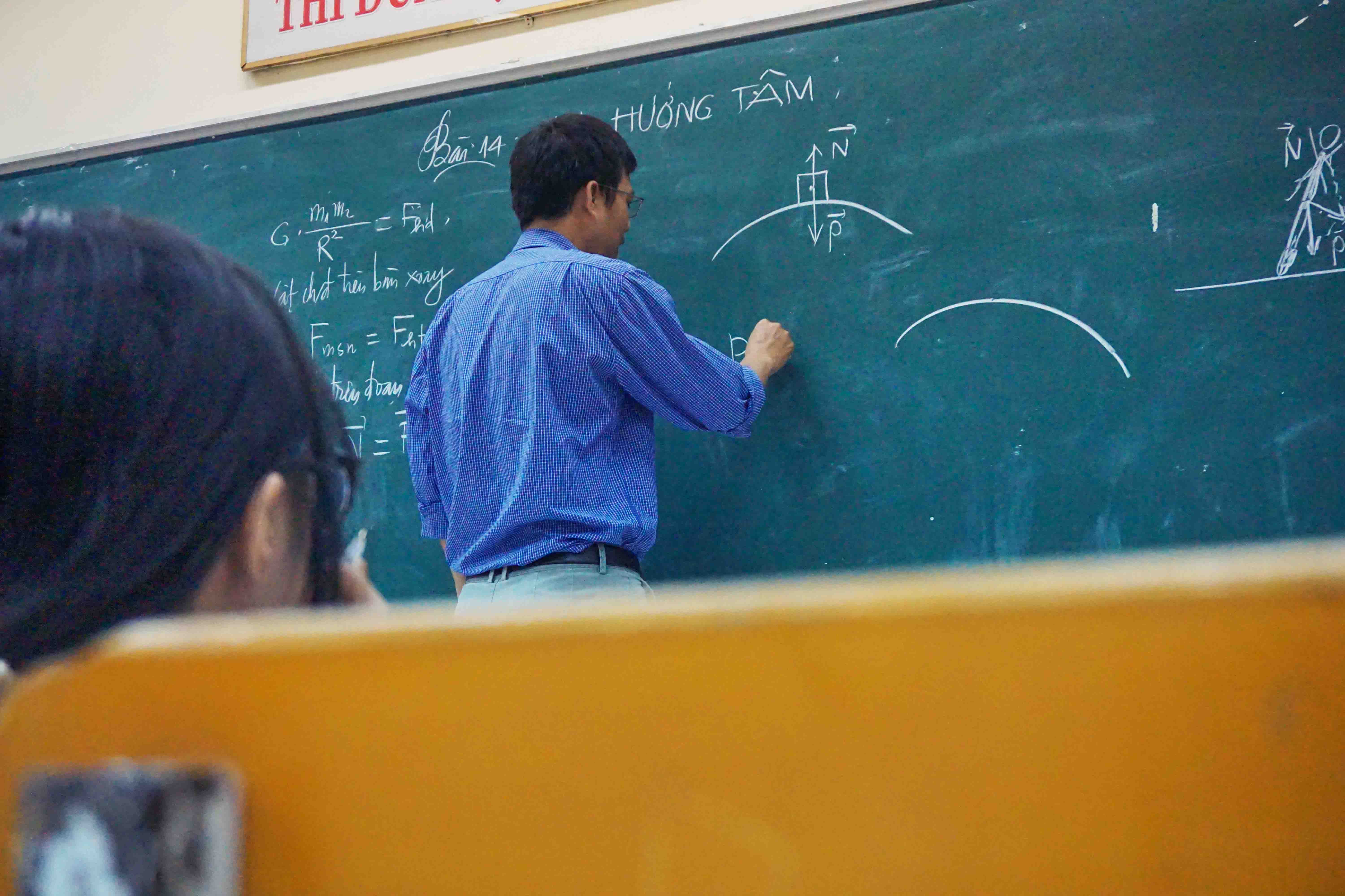 professor writing a formula on a classroom blackboard