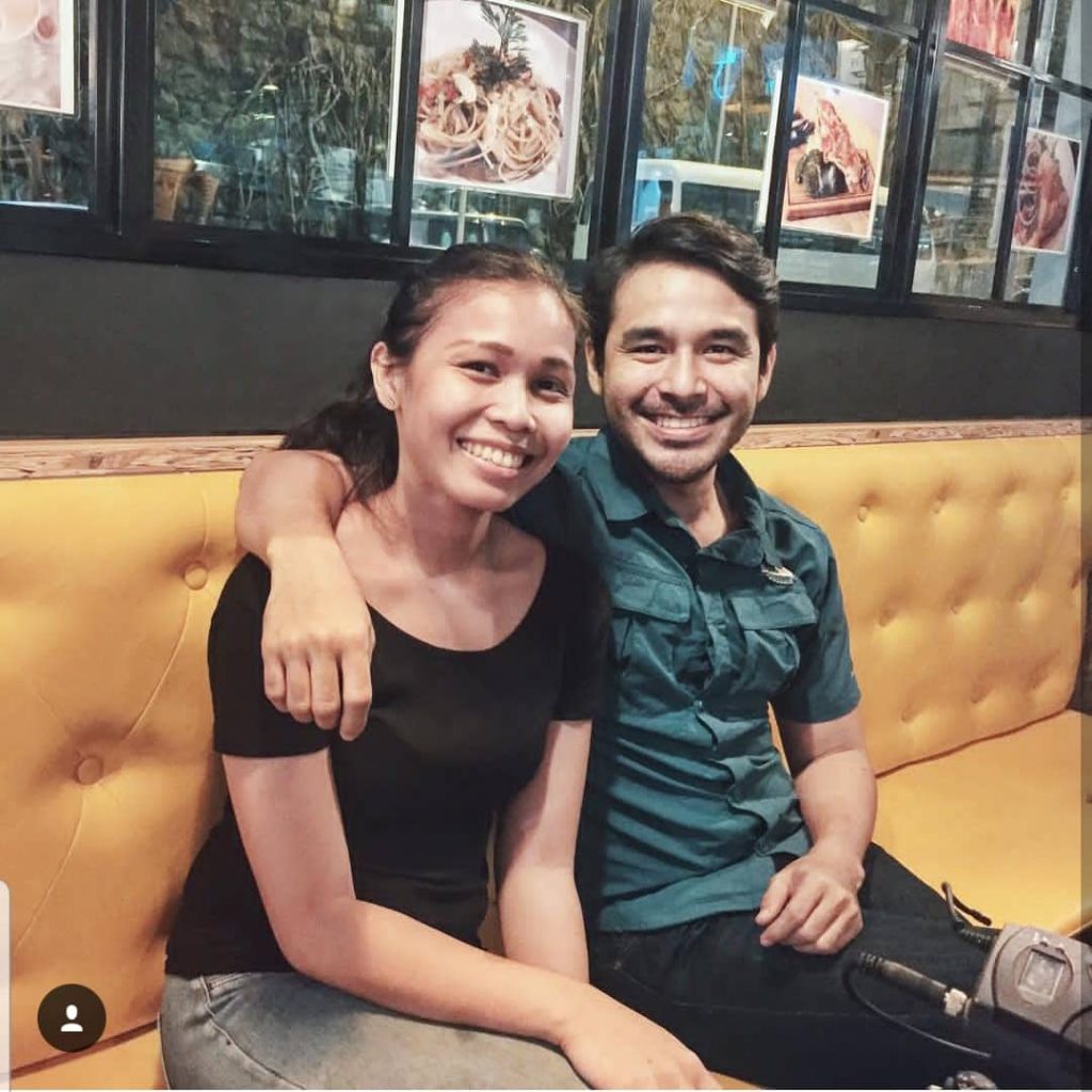 woman and man sitting on a couch, smiling to camera