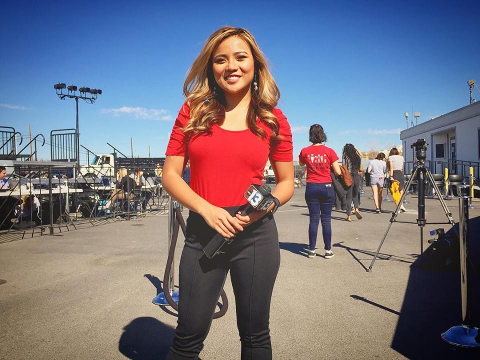female reporter holding a microphone while looking to camera