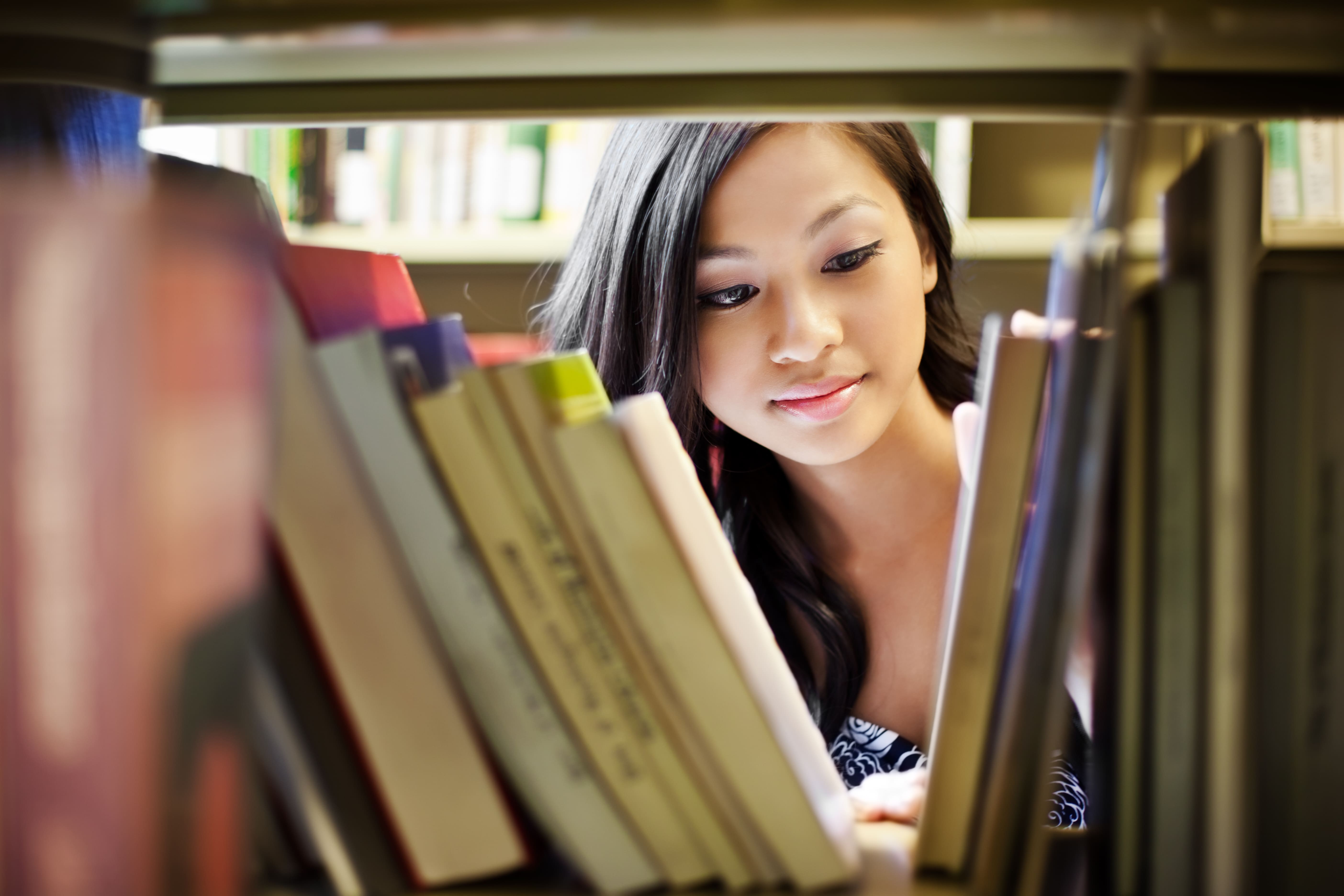 female student looking through books in a library