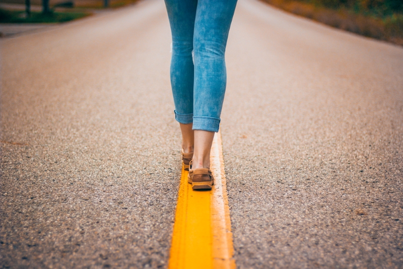 Girl walking along yellow line in the middle of the road