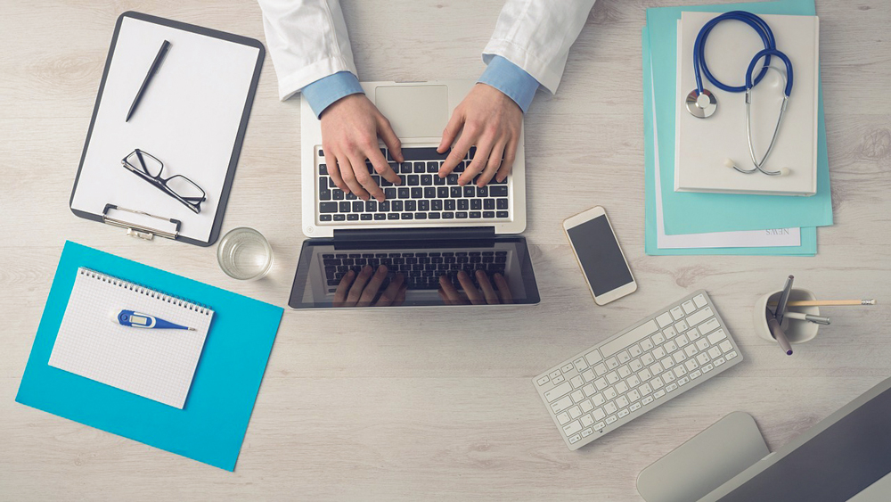 person wearing a lab gown while working on a laptop