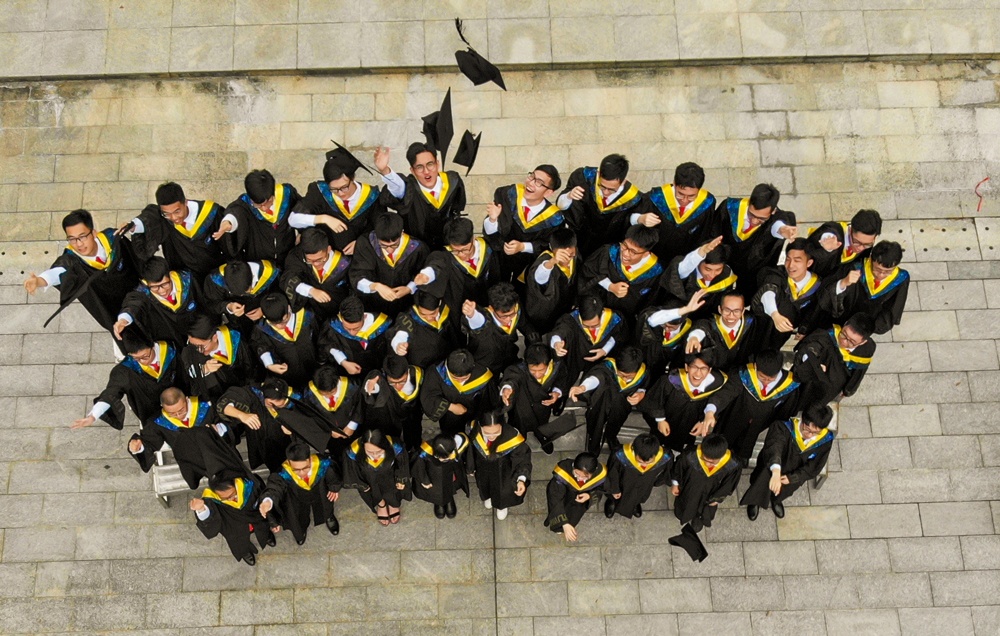 graduating class together throwing toga caps