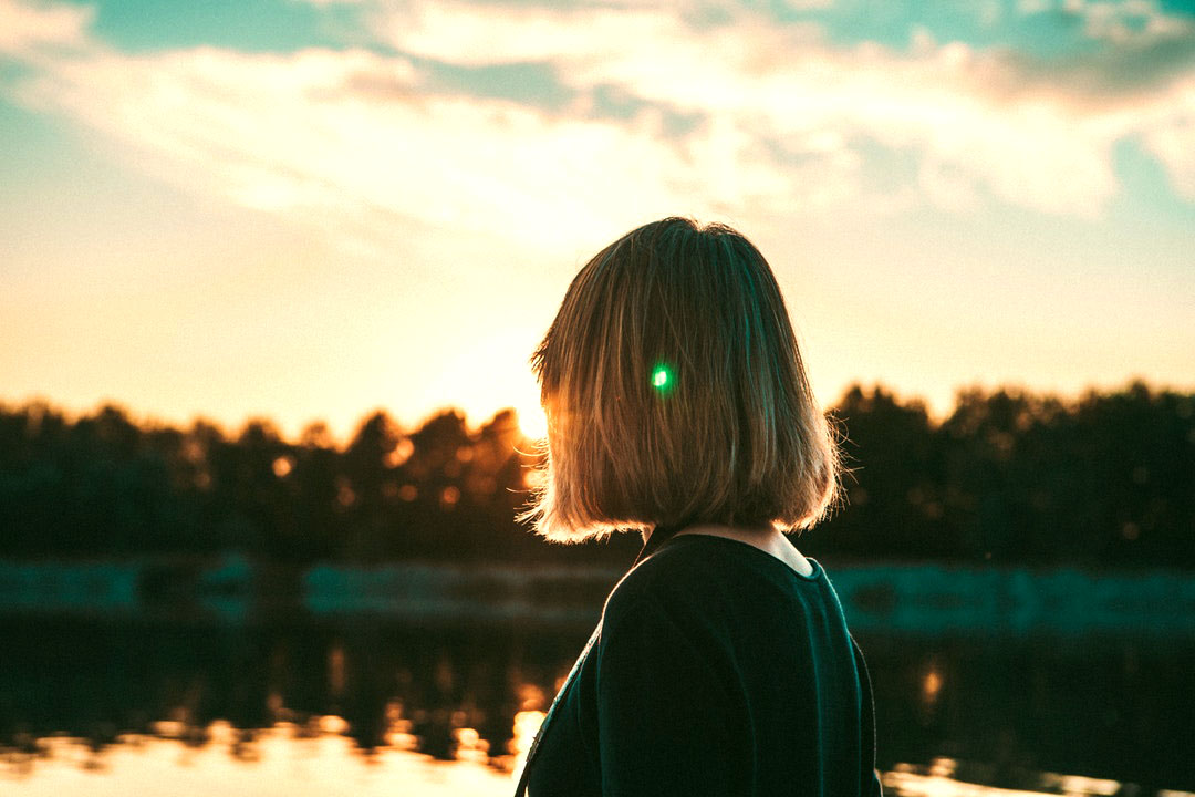 girl looking out onto a lake