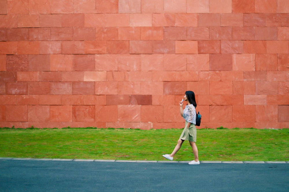 girl holding ice cream while standing in front of red brick wall
