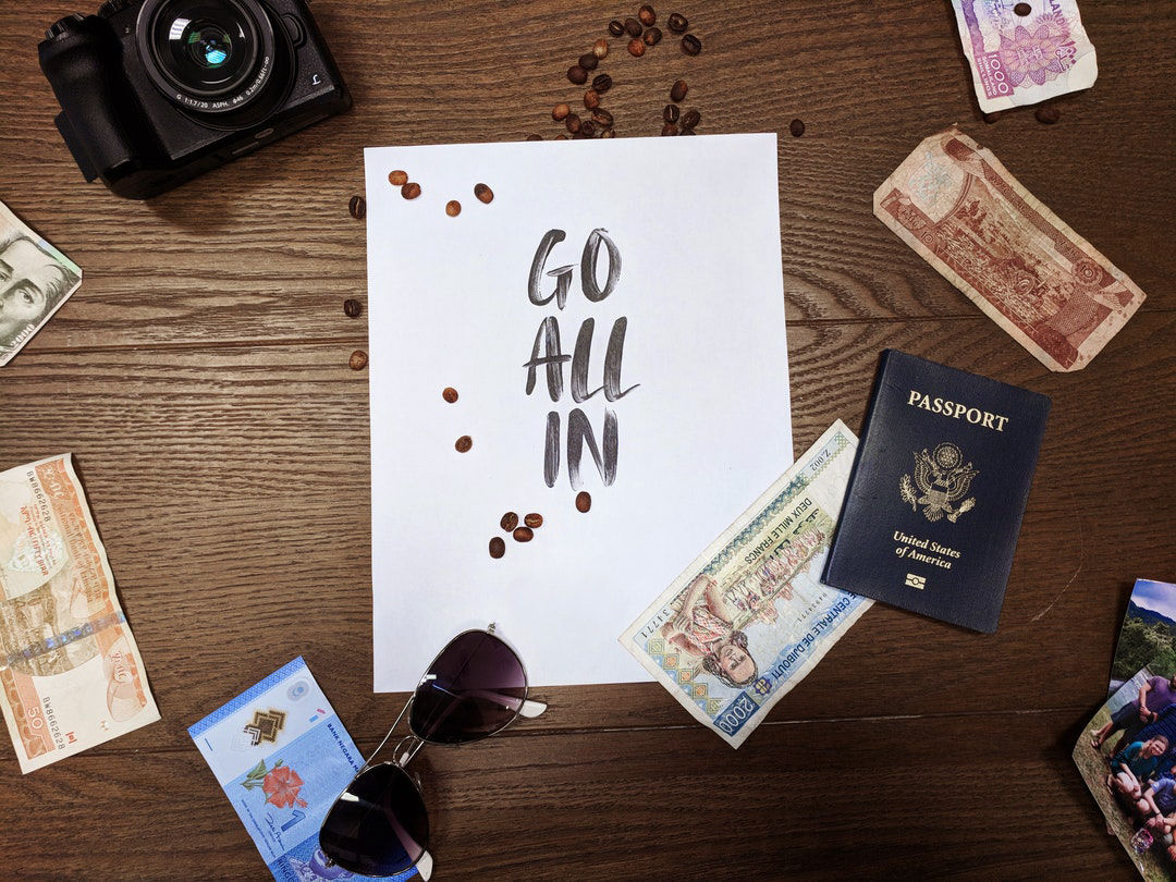 USA passport and money scattered on a table, words "go all in" written on a paper