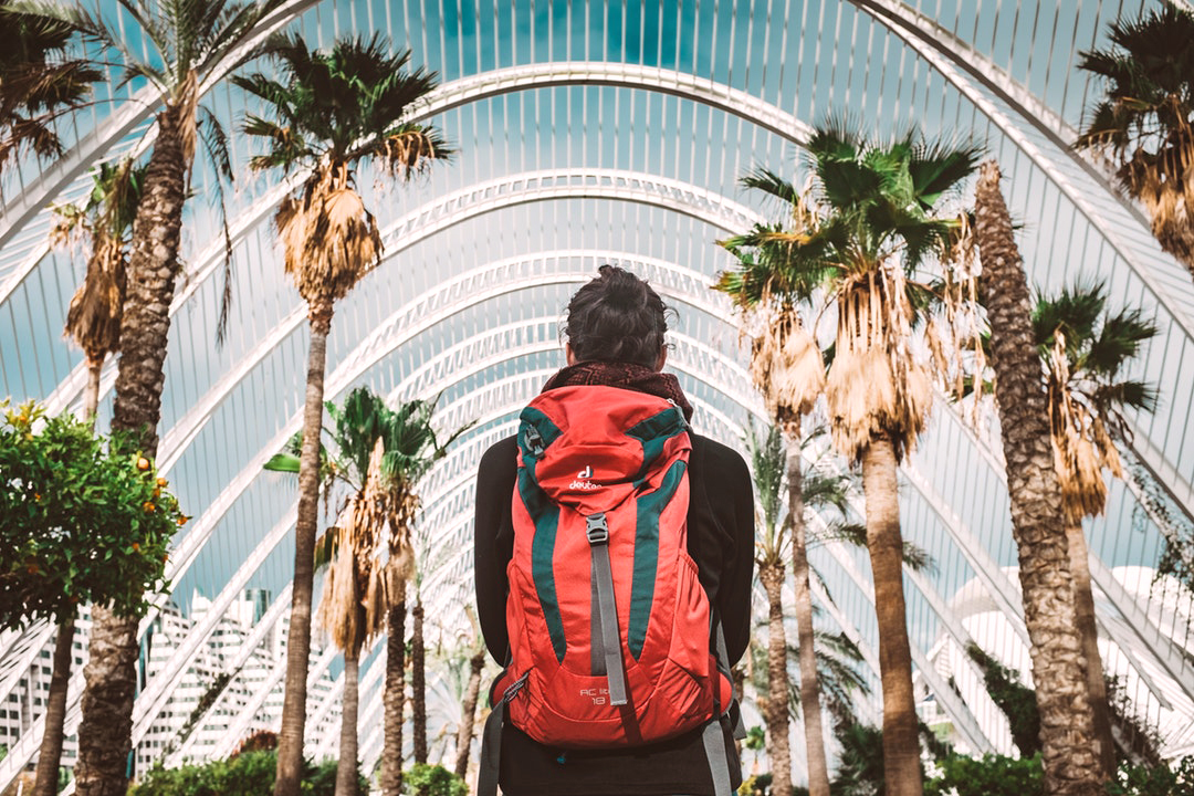 girl carrying backpack and facing a wide path of trees