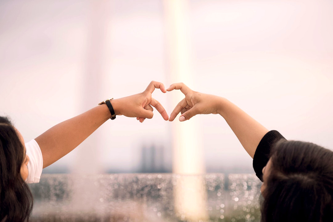 two people's fingers forming a heart shape