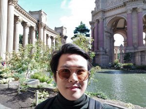 Man in shades posing in front of a fountain