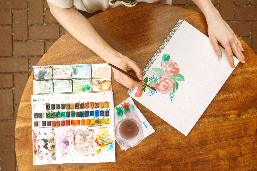 flay lay photography of person painting pink flowers