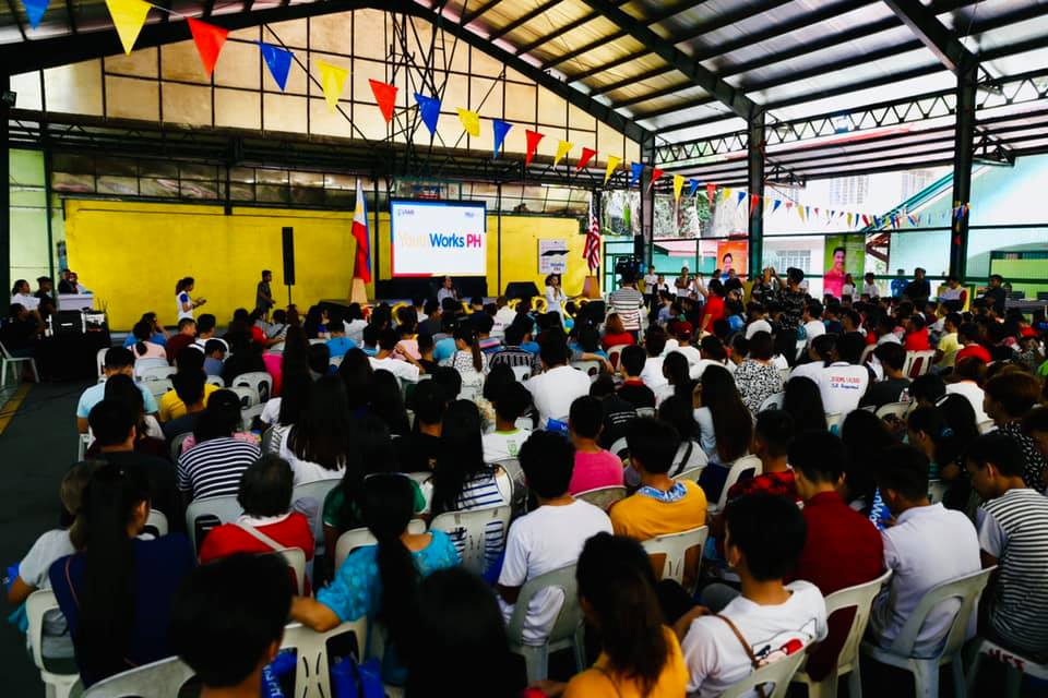 seated audience listening to person speaking on microphone