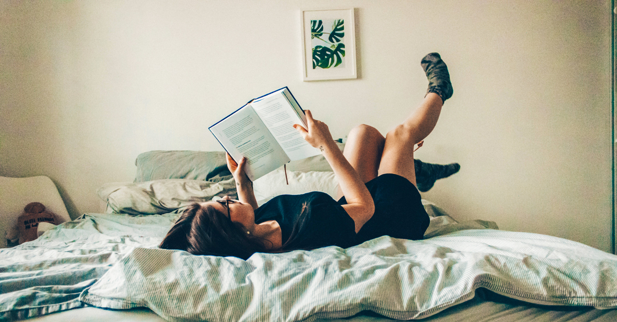 girl on a bed reading a book about the humanities