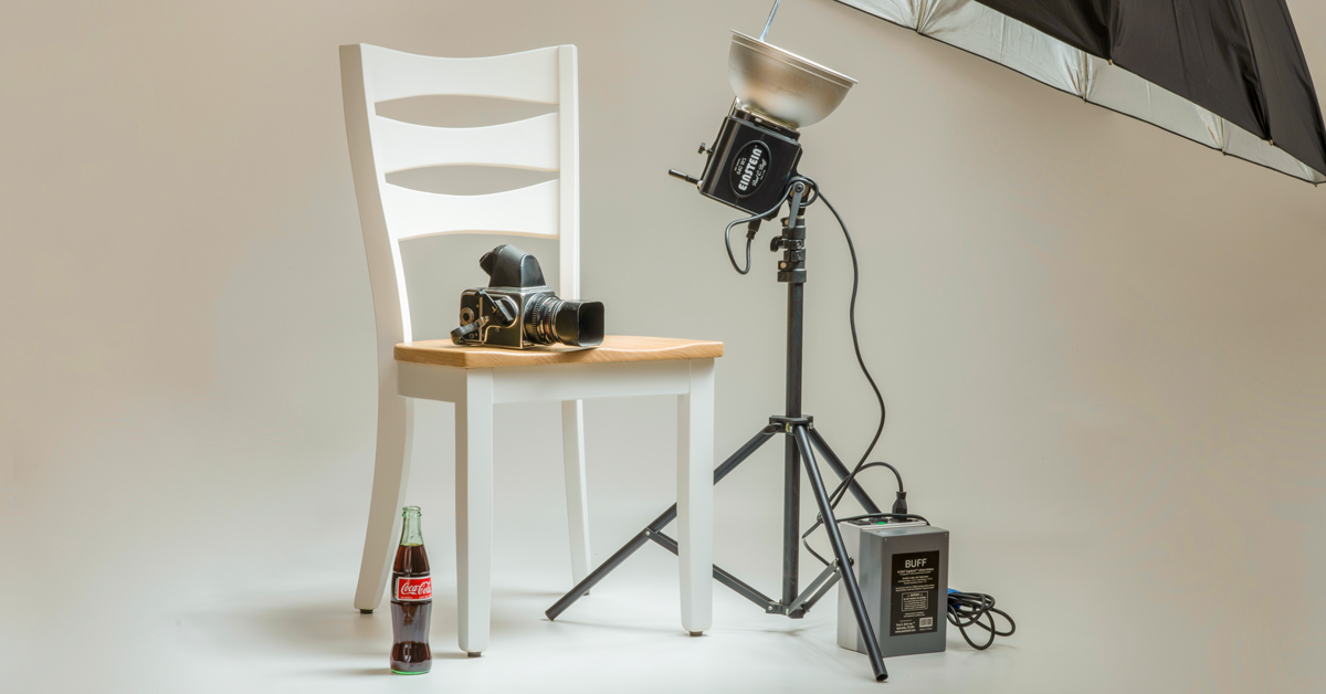 photo studio with camera, lights, chair, and bottle product