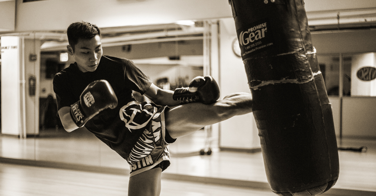 man kicking punching bag