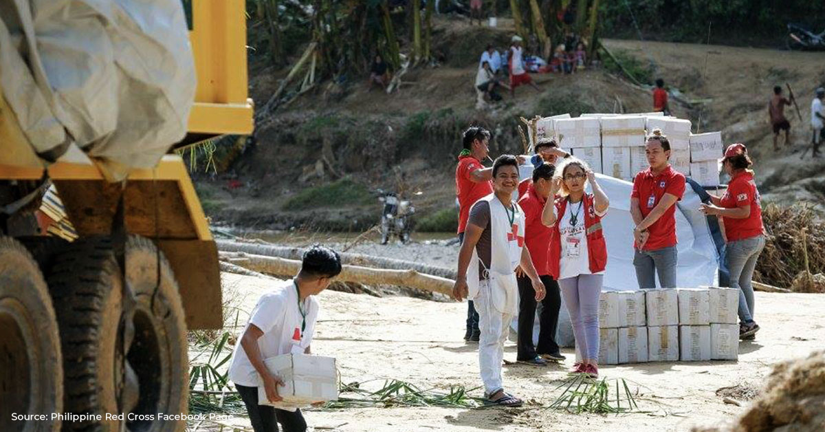student volunteers standing beside boxes of relief goods