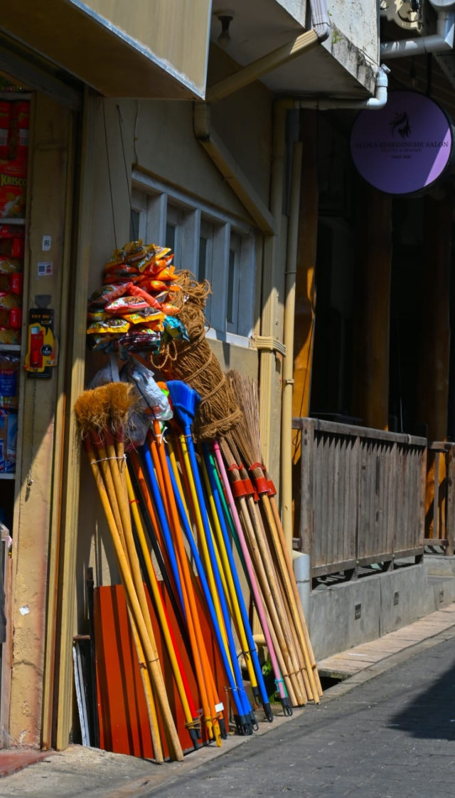 Colorful Brooms and Everyday Goods on a Sunlit Street”