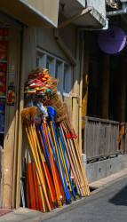 Colorful Brooms and Everyday Goods on a Sunlit Street”