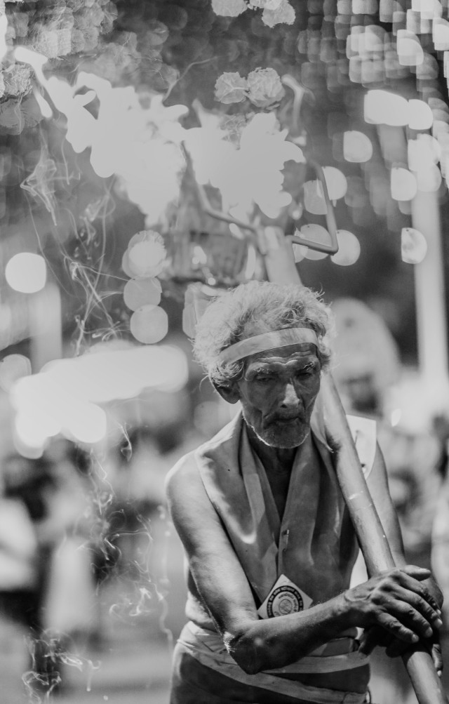A devoted person who lights the way, ensuring the beauty of the magnificent procession is not hidden in the dark, but seen by the people. For many years, he has dedicated his sweat and effort to this duty, driven by the deep devotion in his heart.