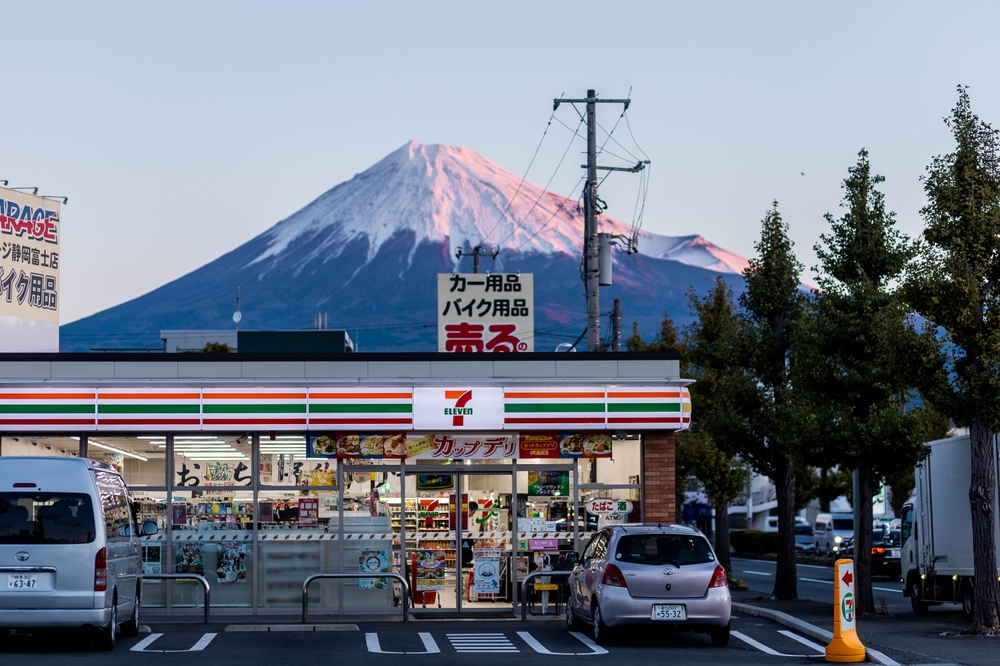 External facade of a 7-11 convenience store with Mount Fuji behind in the town of Fuji, Shizuoka.