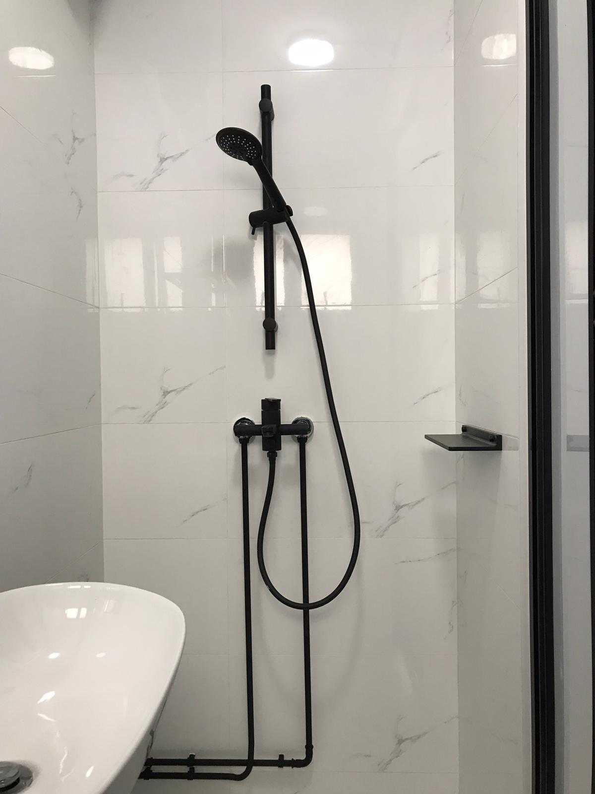 Minimalist Bathroom with Homogeneous Tiles and Showers