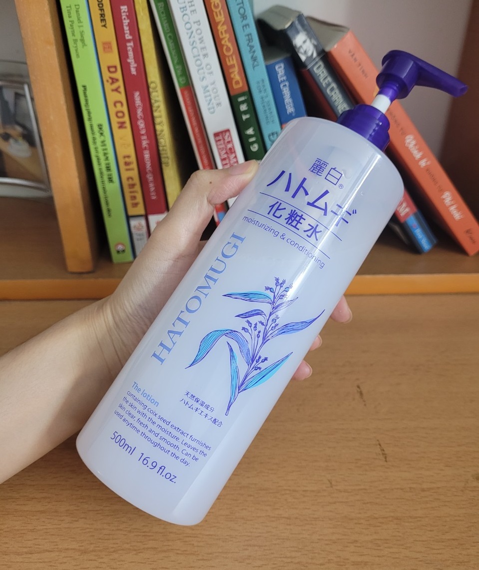 Lọ lotion Hatomugi 500ml trên bàn làm việc, bên cạnh nhiều cuốn sách. Bài viết chia sẻ skincare routine buổi tối hiệu quả với kinh phí dưới 1 triệu đồng, kèm review sản phẩm như sữa rửa mặt Eucerin, kem dưỡng I'm From Vitamin Tea Tree.