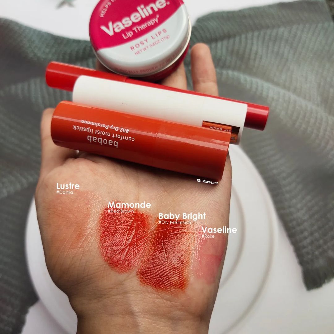Bộ sản phẩm son dưỡng có màu với thông tin về các thỏi son như Vaseline, Mamonde, Baby Bright và Lustre trên tay người dùng. Bài viết "Đọ sức" 4 thỏi son dưỡng có màu sẽ khám phá đâu là lựa chọn tốt nhất cho cô nàng môi khô, kết hợp cả dưỡng ẩm và tươi tắn.