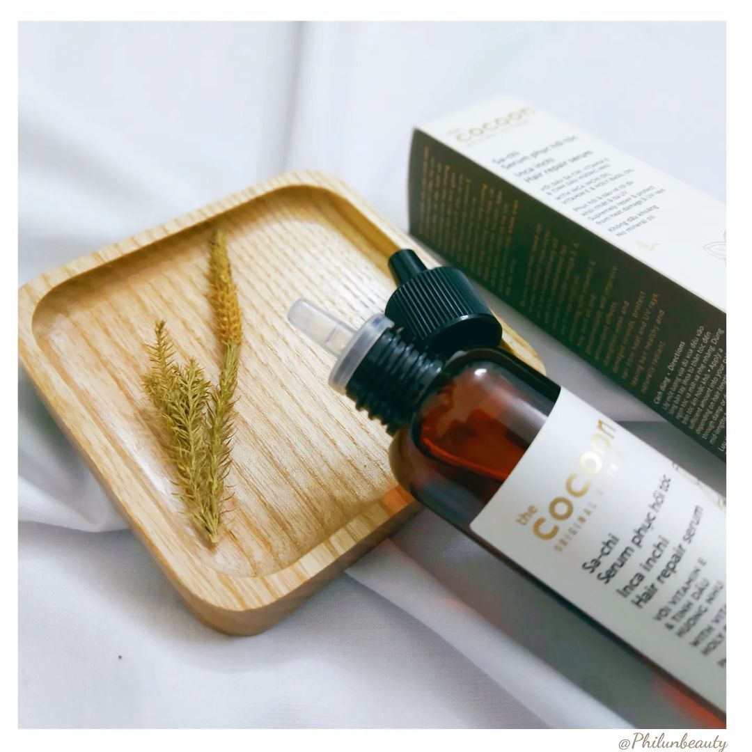Serum dưỡng tóc từ tinh dầu Sachi của Cocoon, với chai bơm nhỏ gọn, trên khay gỗ có vài cành cây khô. Được Beauty Reviewer Phí Huyền Trang khen ngợi là serum phục hồi tóc hư tổn tốt nhất, mang lại kết quả nhanh chóng.