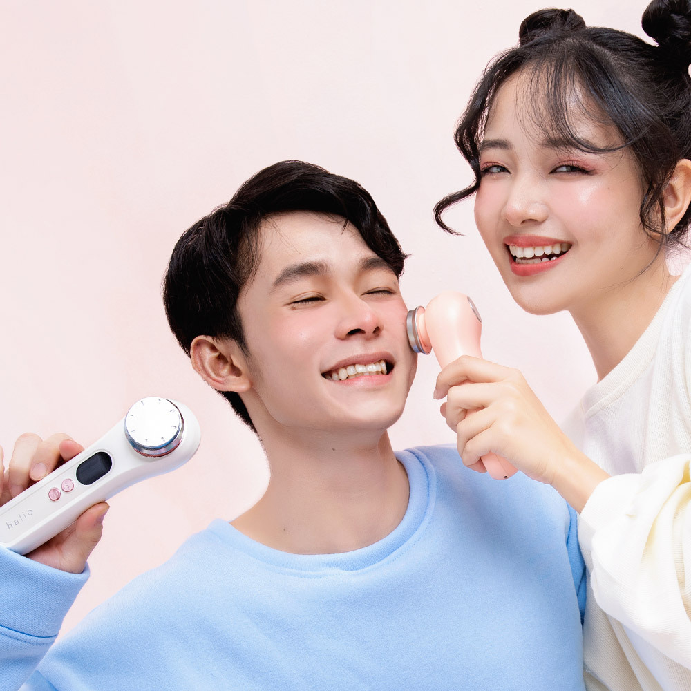 Cặp đôi vui vẻ cùng nhau sử dụng thiết bị chăm sóc da Halio Sonic PRO và bàn chải điện Halio Sonic, thể hiện sự quan tâm và yêu thương, cùng nhau chăm sóc bản thân với các dụng cụ làm đẹp high-tech.