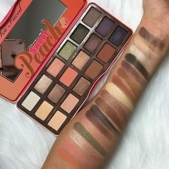 Bảng phấn mắt Sweet Peach từ Too Faced, thể hiện màu sắc sống động với các tông màu từ nude đến đậm. Mẫu swatch phấn trên cánh tay cho thấy độ lên màu tốt và sự đa dạng trong bảng màu, là sự lựa chọn hoàn hảo cho các tín đồ trang điểm.