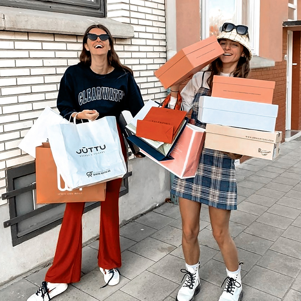 Hai cô gái vui vẻ đang giữ nhiều túi shopping, biểu tượng cho hoạt động mua sắm trong Ngày Quốc tế Hạnh phúc 20 tháng 3. Bài viết "6 điều nhất định phải làm trong ngày Quốc tế Hạnh phúc" sẽ gợi ý cho bạn cách tìm niềm vui và lan tỏa năng lượng tích cực.