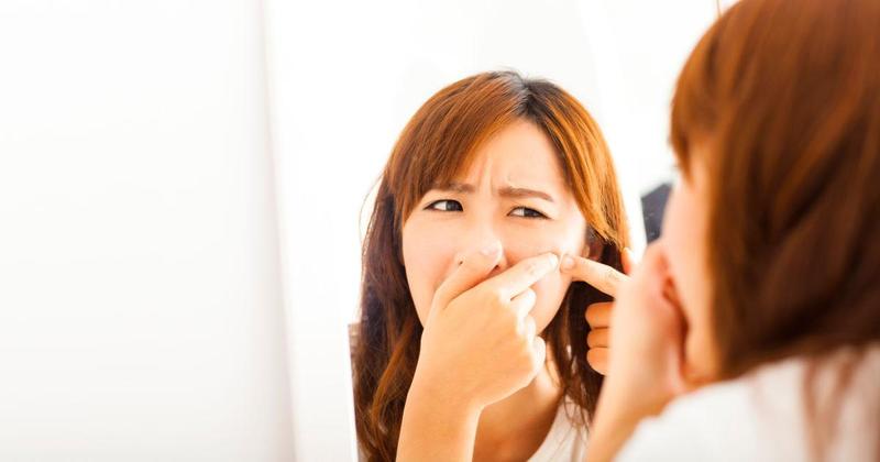 Một người phụ nữ đang chăm sóc da mặt, nhìn vào gương với vẻ mặt lo lắng khi thấy mụn. Bài viết có tiêu đề "NHỮNG THÀNH PHẦN DƯỠNG DA" đề cập đến các giải pháp và thành phần hiệu quả trong dưỡng da.