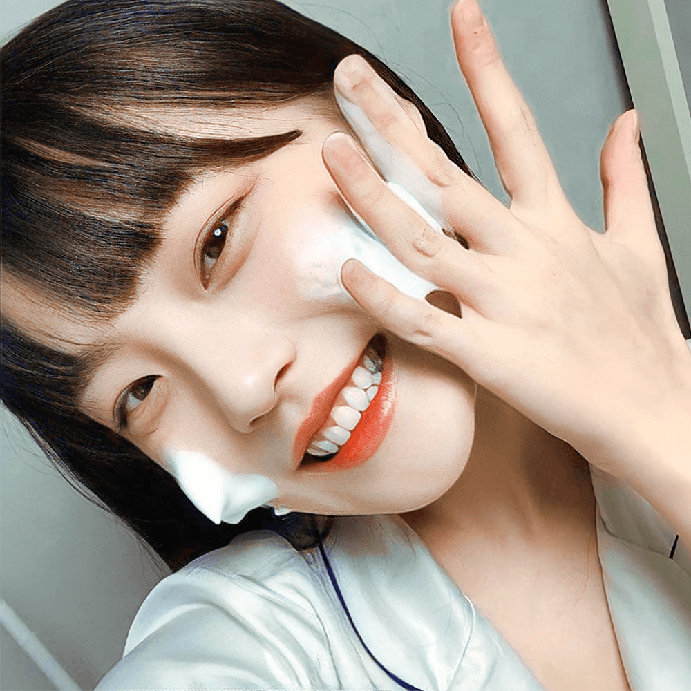 Một người phụ nữ trẻ tuổi đang rửa mặt với sản phẩm chăm sóc da, nụ cười rạng rỡ thể hiện sự tự tin và hào hứng với quá trình làm đẹp. Bài viết từ Lixibox giải đáp thắc mắc về việc dùng mỹ phẩm bao lâu thì thấy kết quả, đặc biệt là sản phẩm dưỡng da và vitamin C.