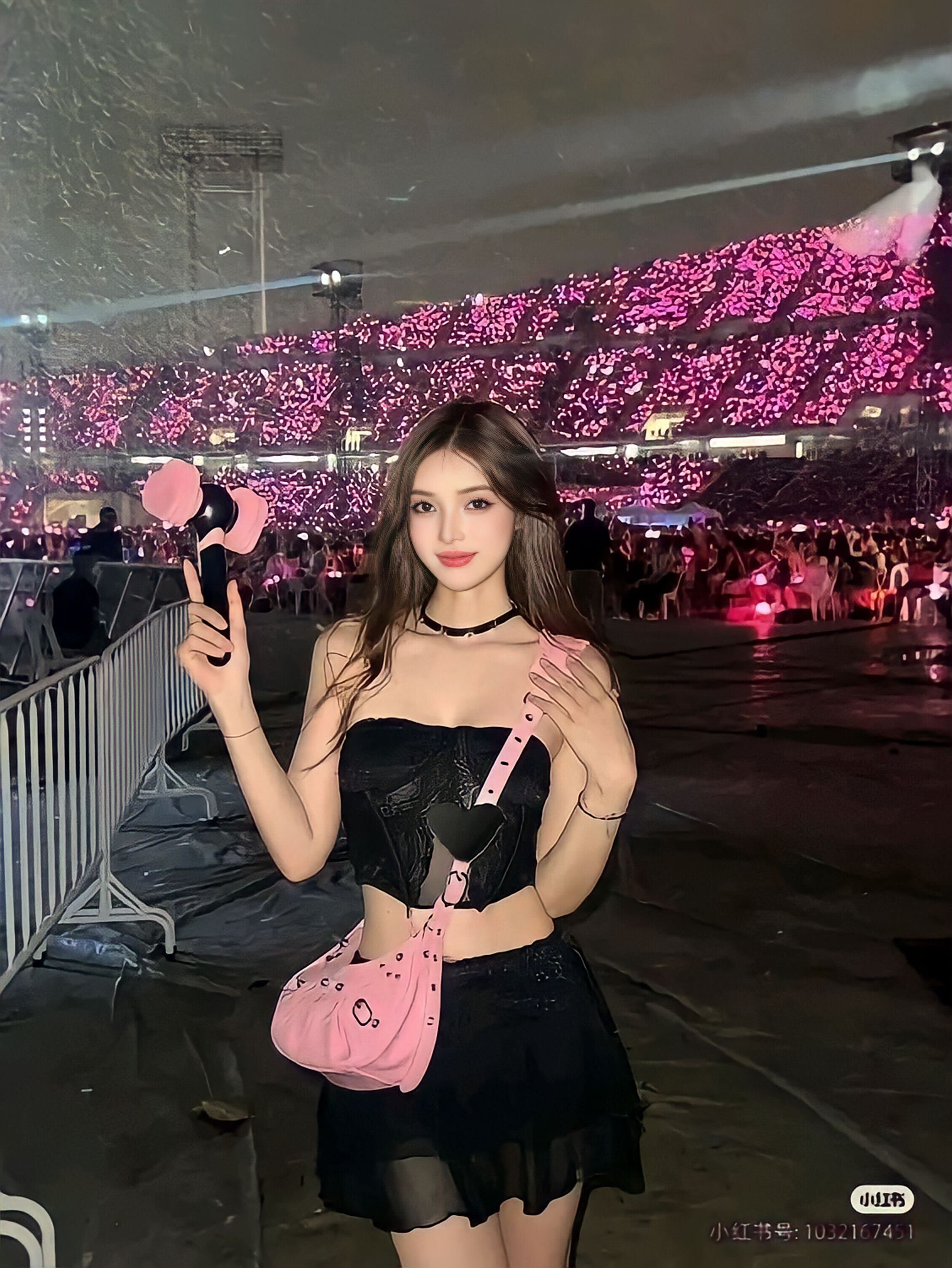 Một cô gái trẻ đứng giữa không gian concert, mặc áo crop top đen và chân váy đen, cầm quạt cổ điển, phía sau là đám đông khán giả với ánh sáng hồng rực rỡ. Bài viết chia sẻ cách ăn mặc đẹp khi đi concert để tạo ấn tượng và thoải mái khi thưởng thức âm nhạc.